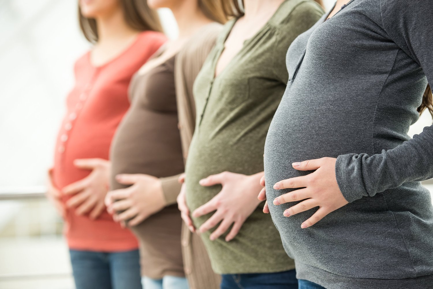 four pregnant women holding bellies