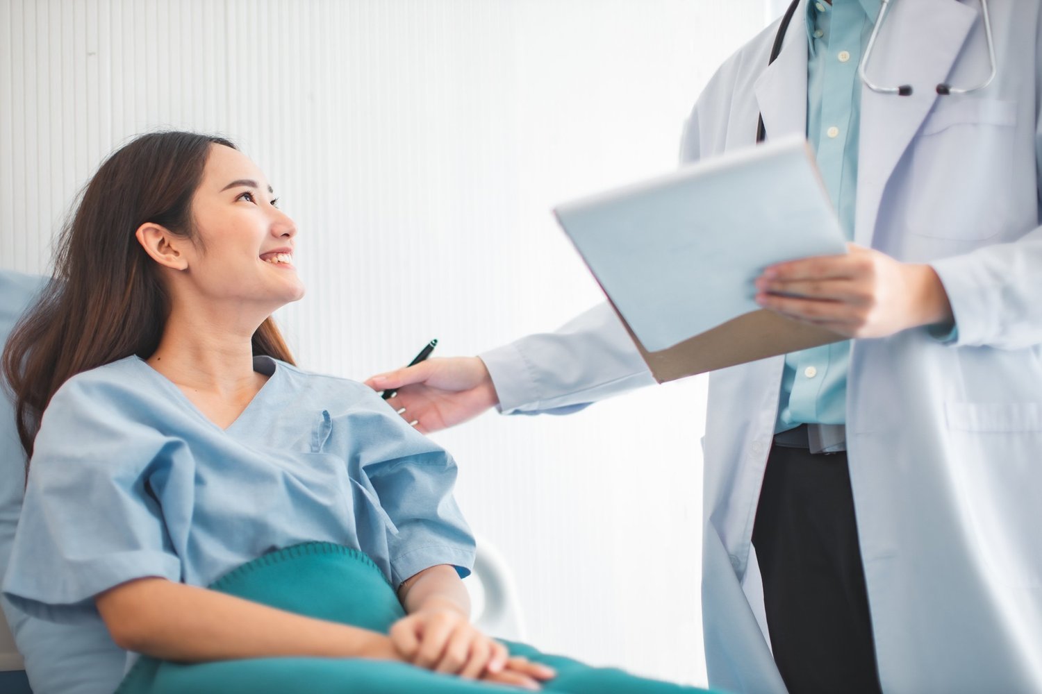 Woman in hospital gown talking to doctor