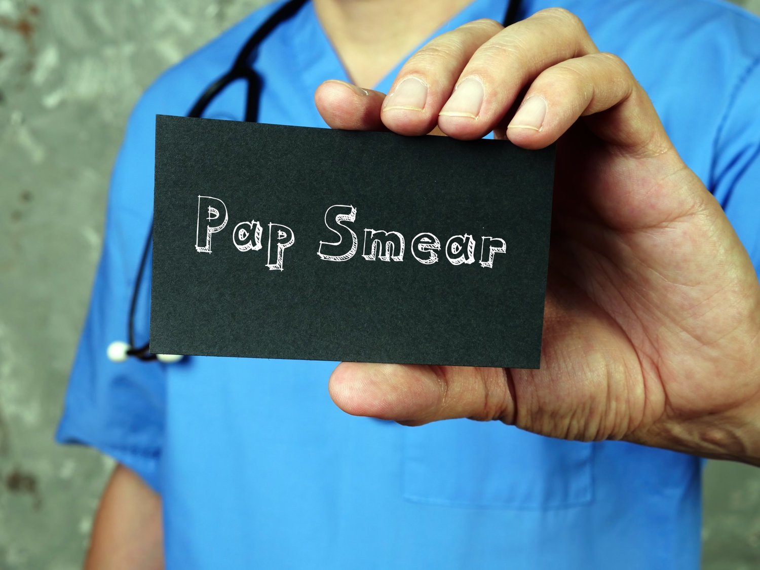 Medical professional holding card that says "pap smear"