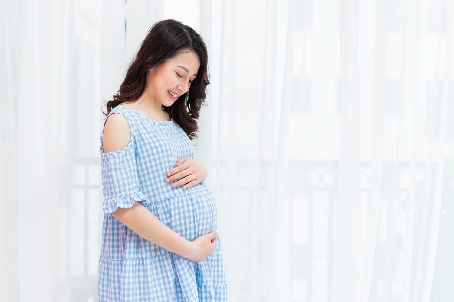 Woman in blue dress holding pregnant belly
