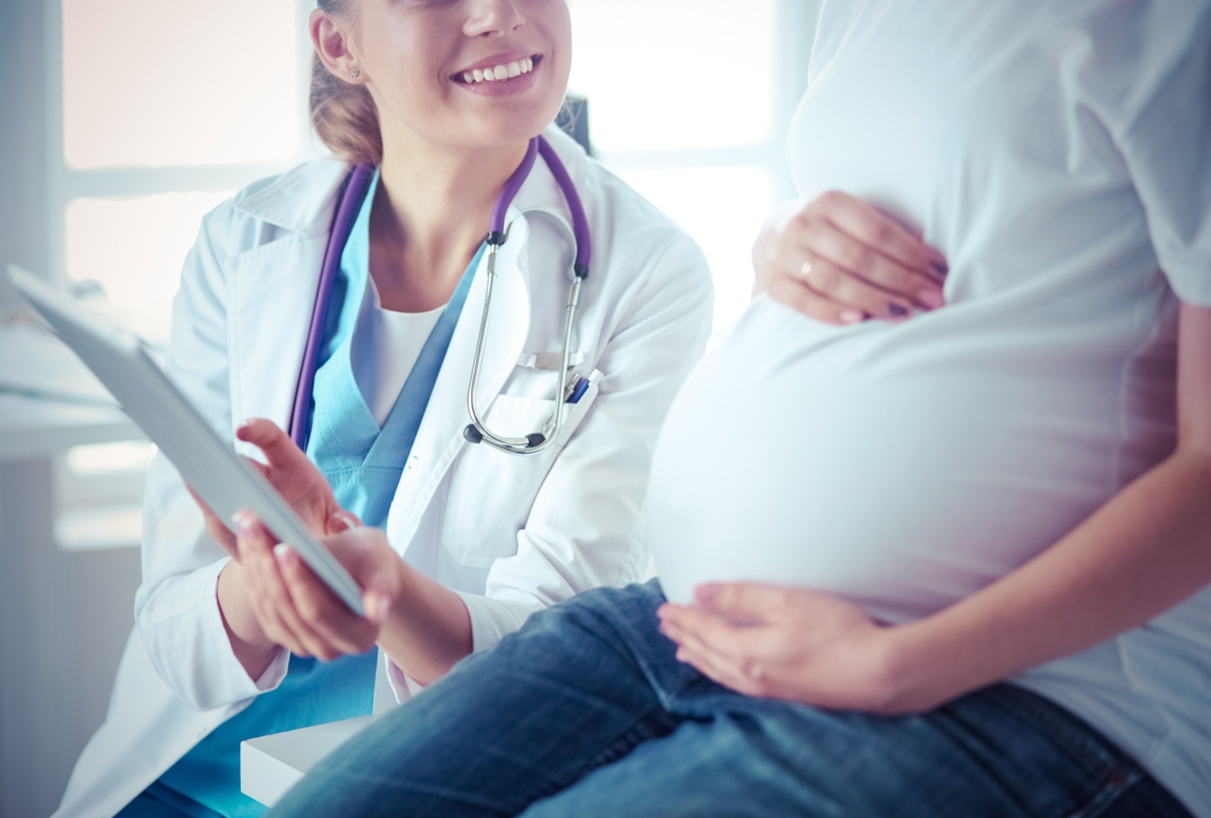 Pregnant woman holding her belly while talking to a doctor