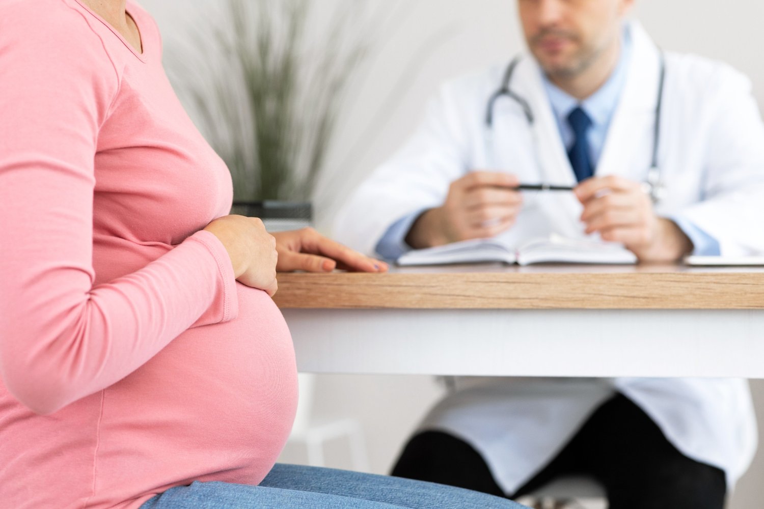 Pregnant woman holding belly while talking to doctor