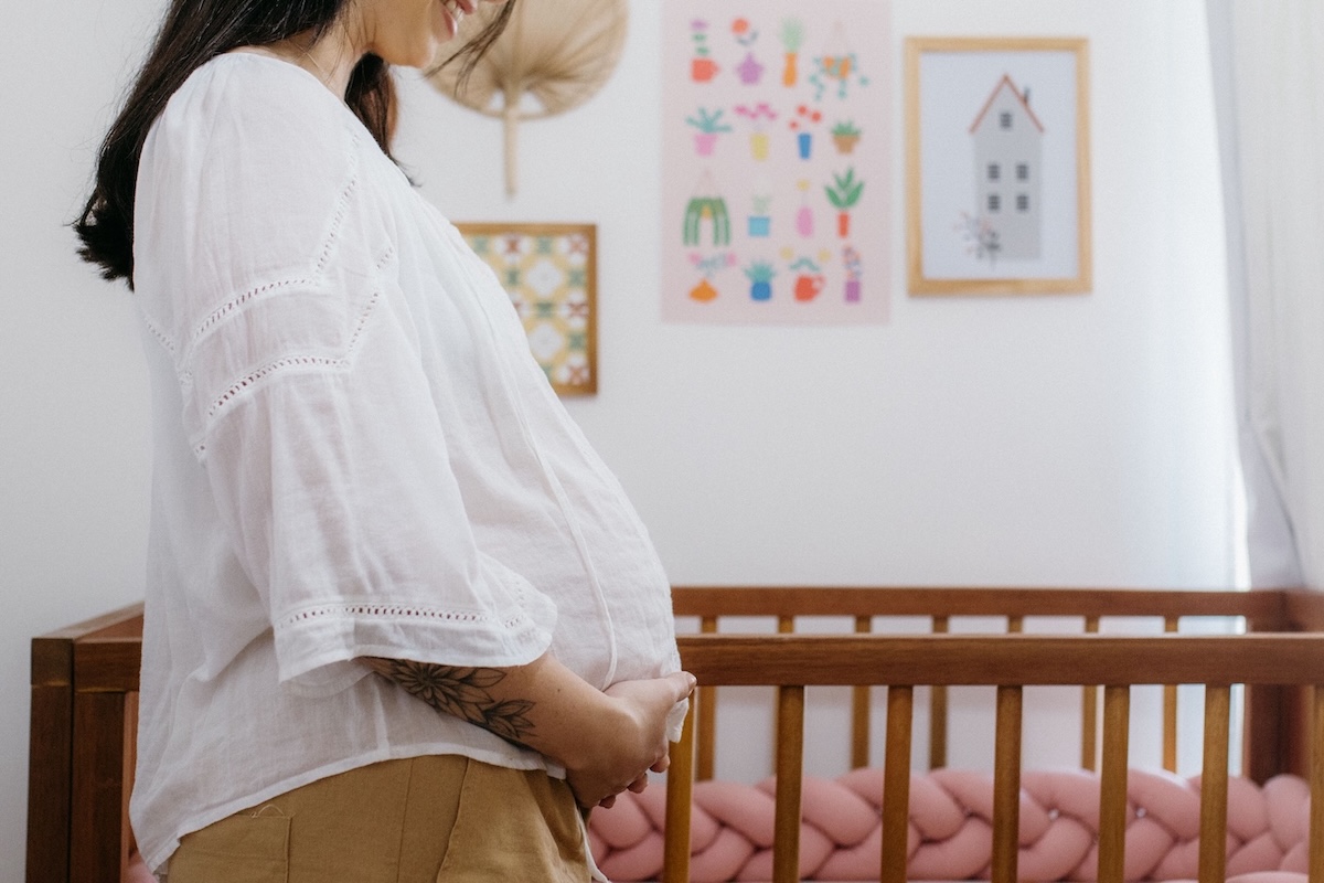 Woman in a nursery holding her baby bump.